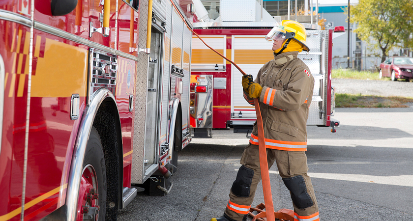 picture of a fire fighter pulling a fire hose out of a fire truck